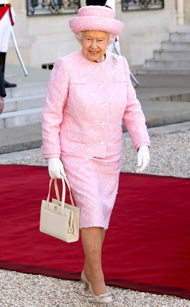 The Queen of England in a pink outfit with pearls and gorgeous hat.