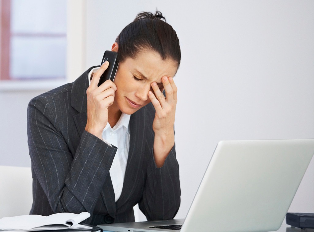 Tensed middle aged business woman using a cellphone at work