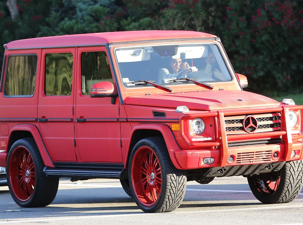 Kylie Jenner driving a custom red Mercedes-Benz G-Wagon with matching red rims.