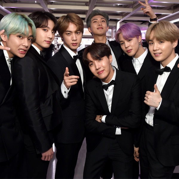 BTS sonriendo a la cámara con trajes negros en los Grammys 2019