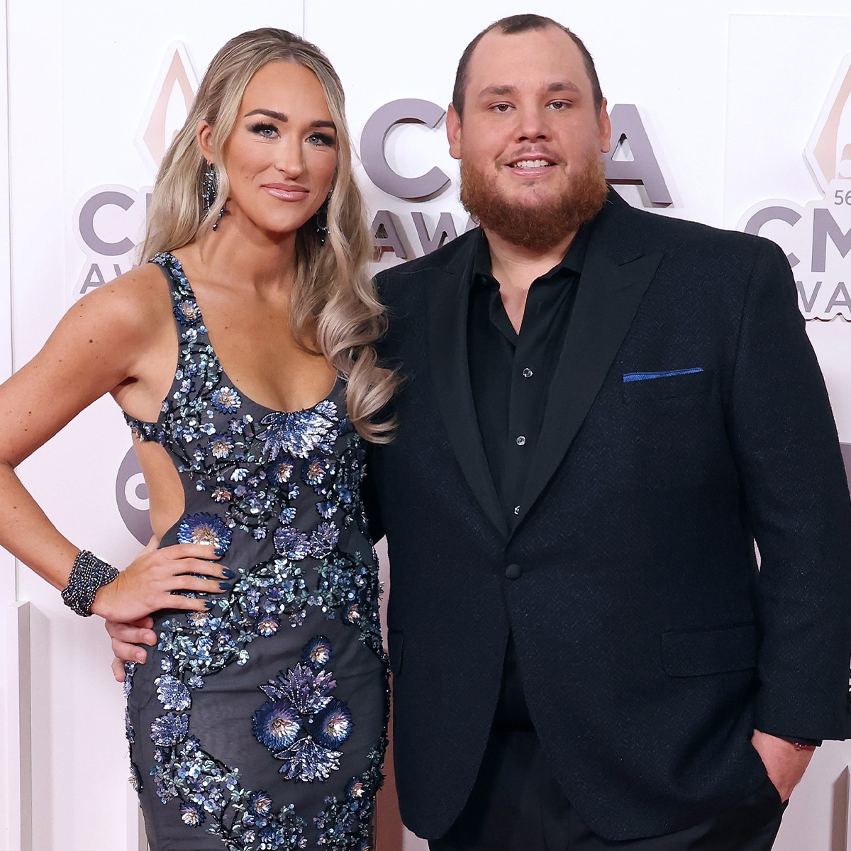 Luke Combs and his wife Nicole Hocking posing together on the red carpet at the CMA Awards, dressed in formal eveningwear
